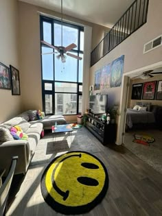 a living room filled with furniture and a large yellow smiley face rug on the floor