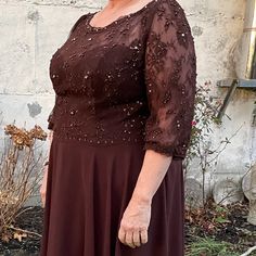 an older woman in a brown dress posing for the camera with her hand on her hip