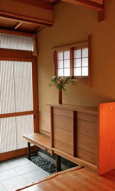 a wooden bench sitting in front of a window next to a plant on top of a table