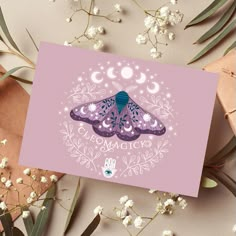 a card with a purple butterfly on it next to some white flowers and greenery