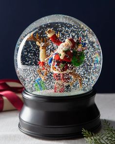 a snow globe with santa claus and reindeers in it on top of a table