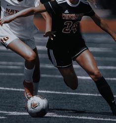 two girls are playing soccer on the field