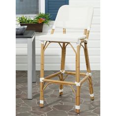 a white stool sitting on top of a stone floor next to a table and potted plant