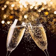 two champagne flutes are being toasted with sparkling confetti in front of a black background