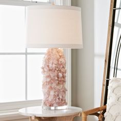 a pink lamp sitting on top of a table next to a mirror and chair in a room