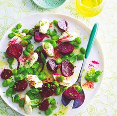 a white plate topped with beets and green beans next to a bowl of mustard