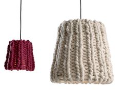 two knitted lamps hanging from cords on a white wall, one in red and the other in purple