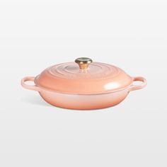 a pink casserole dish with a gold lid on a white background, it is also available for use as an appliance