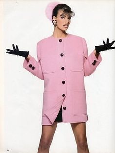 a woman in a pink coat and black shorts with her hands out to the side