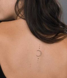 the back of a woman's shoulder with a small crescent tattoo on her left side