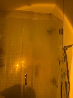 a bathroom with yellow light coming in from the shower