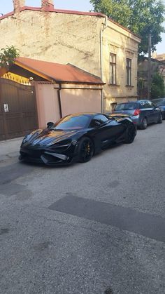 two black sports cars parked in front of a building on the side of a street