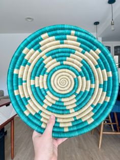 a person holding up a blue and white basket in front of a dining room table