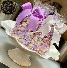 a white bowl filled with lots of purple and white candies on top of a table