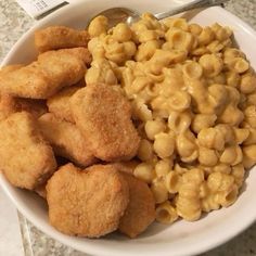 a white bowl filled with macaroni and cheese next to fried chicken nuggets