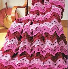 a crocheted blanket sitting on top of a chair next to a wooden chair