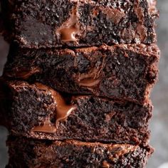 a stack of brownies with chocolate frosting on top and one cut in half