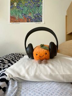 a crocheted pumpkin with headphones sitting on top of a pillow in a bed