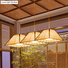 a bamboo lamp hanging from the ceiling over a table with chairs and potted plant