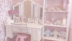 there is a white desk with pink accessories on it and a mirror in the corner