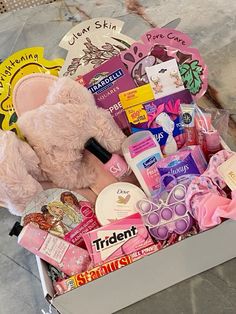 a pink teddy bear sitting inside of a box filled with lots of different types of items