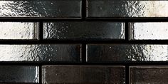 a close up view of a black brick wall with white and silver foil on it