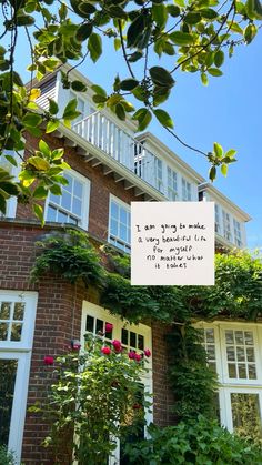 a brick house with vines and flowers growing on the front porch, next to a sign that says i am going to make a very special trip