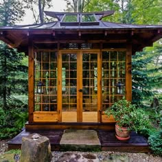 a small wooden structure with glass doors in the middle of some rocks and trees around it