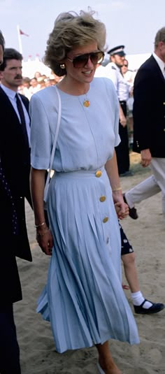 a woman in a blue dress walking next to a man