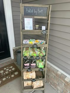 a wooden shelf filled with lots of food on top of a front porch next to a door