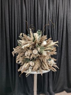 an arrangement of dried flowers is displayed on a stand