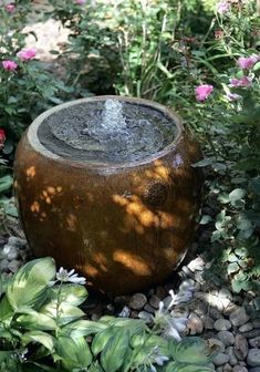 a water fountain surrounded by flowers and rocks