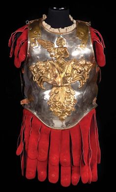 an armor with gold and red accents on the chest is displayed in front of a black background