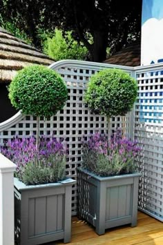 two gray planters sitting on top of a wooden floor next to a white fence