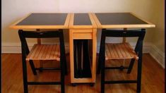 two wooden chairs sitting at a table with black glass top