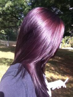 the back of a woman's head with long purple hair and an electric razor in her hand