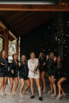 a group of women standing next to each other in front of a building with confetti