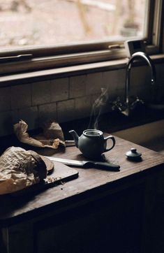 a table with a tea pot, knife and paper on it next to a window