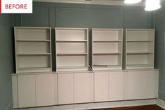 an empty room with white bookcases and wood flooring in front of it