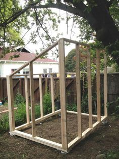 a wooden structure sitting in the middle of a yard next to a tree and fence