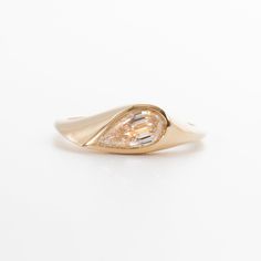 a yellow gold ring with an oval shaped diamond in the center, on a white background