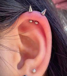 an ear with three different piercings attached to the middle of it, and two smaller ones