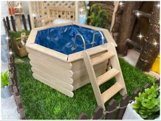 a wooden toy swimming pool with ladders on the ground and green grass around it