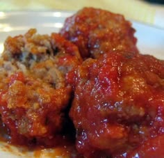 some meatballs are in a white bowl with sauce on it and is ready to be eaten