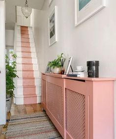 a hallway with pink painted stairs and rugs