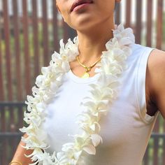 a woman wearing a white flower lei with gold necklace and ring on her left hand