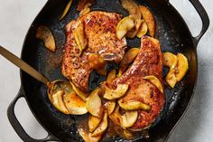 chicken with lemons and onions in a skillet on a marble countertop next to sliced lemons