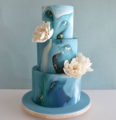 a three tiered blue cake with flowers on top