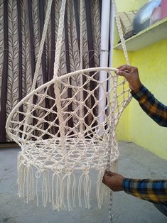 a man is holding up a white macrame