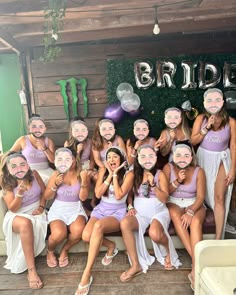 a group of young women posing for a photo in front of a sign that says bride